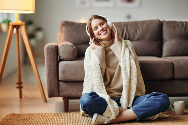 Sıcak Battaniyeli Keyifli Genç Bir Bayan Gülümsüyor Evdeki Kanepenin Yanında — Stok fotoğraf