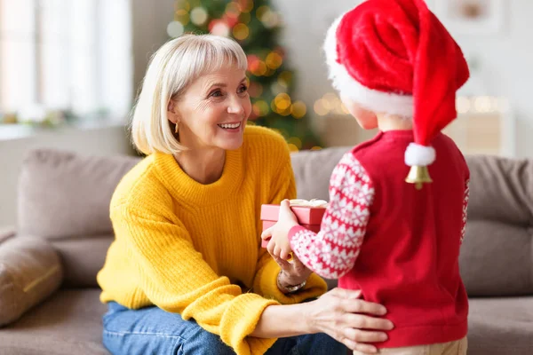 Wesoła Babcia Dostaje Prezent Świąteczny Nierozpoznawalnego Wnuczka Podczas Świętowania Wakacji — Zdjęcie stockowe