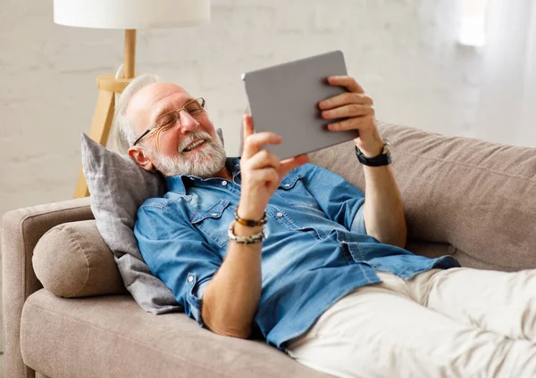 Optimistický Vousatý Starší Muž Odpočívající Pohovce Procházející Tablet Víkendu Hom — Stock fotografie