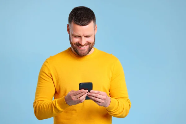 Grappige Vrolijke Man Een Gele Trui Met Smartphone Gekleurde Blauwe — Stockfoto