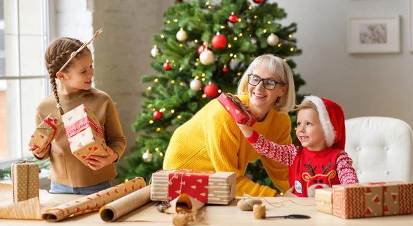 Lindos Hermanos Abuela Envolviendo Regalos Navidad Papel Artesanal Juntos Habitación — Foto de Stock