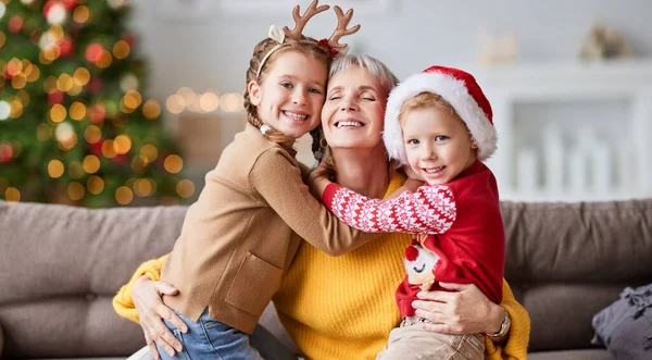 快乐的家庭 成熟的祖母和可爱的孩子坐在沙发上 一边看着相机 一边享受圣诞节的快乐 — 图库照片