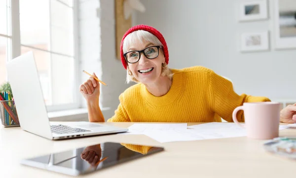 Šťastná Starší Žena Usmívá Dívá Kamery Zatímco Opírá Stůl Pracuje — Stock fotografie