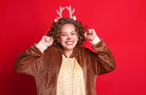 可愛いです面白い若い女性ですクリスマストナカイの衣装笑顔と喜び上のカラフルな赤の背景 — ストック写真