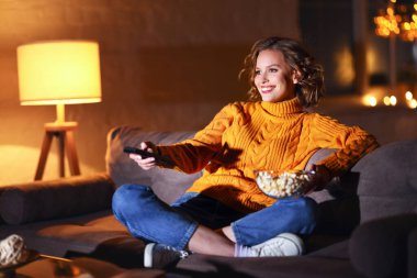 Genç, neşeli bir kadın patlamış mısır yiyor ve kablolu TV 'de film seyrediyor. Bu sırada evde uzaktan kumandayla kanal değiştiriyor.