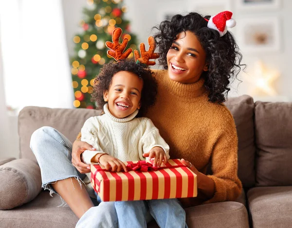 Happy  african american family on holiday: cute kid boy and mother congratulate each other at Christmas present and looking at camer