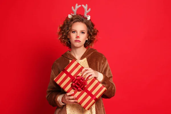 身穿圣诞驯鹿服装 头戴五颜六色红色背衬的年轻女子 看上去很滑稽 很不满意 — 图库照片