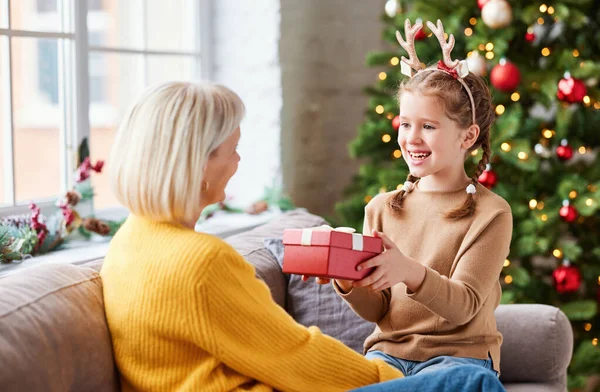 Fröhliche Oma Bekommt Weihnachtsgeschenk Von Kleiner Enkelin Während Sie Urlaub — Stockfoto