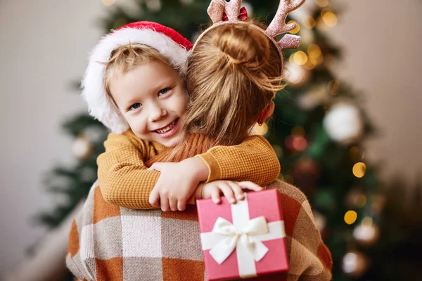 Glückliche Familie Nettes Kind Umarmt Entzückte Mutter Mit Weihnachtsgeschenk Und — Stockfoto