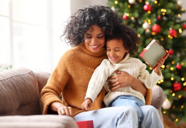 Mutlu Afro-Amerikan ailesi tatilde: tatlı çocuk ve anne Noel 'de birbirlerini tebrik ediyorlar ve hediyelerini açıyorlar. 