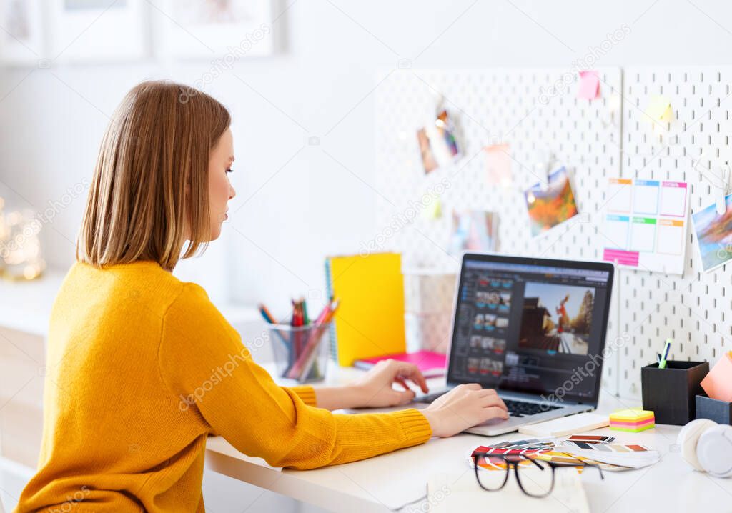 young woman in yellow sweater using laptop for work on design project at home