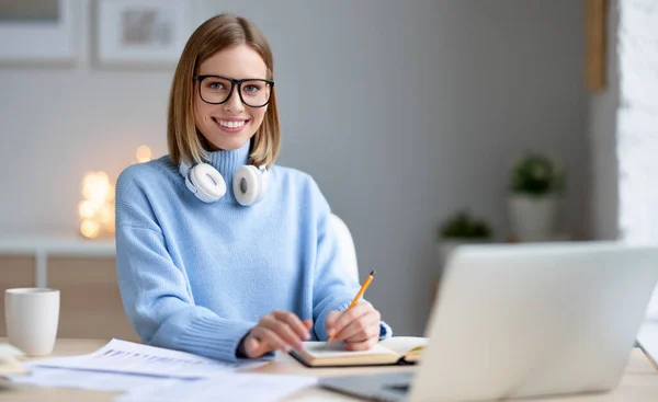 Jovem Feliz Óculos Navegando Dados Laptop Tomando Notas Notebook Enquanto — Fotografia de Stock