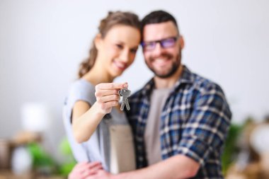 Genç, mutlu, evli bir çift ellerinde ipotekli yeni bir dairenin anahtarlarını tutuyorlar.