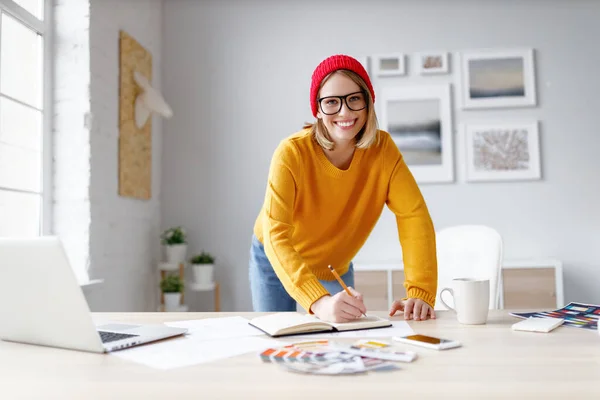 Jovem Feliz Sorrindo Para Câmera Escrevendo Planejador Enquanto Inclina Mesa — Fotografia de Stock