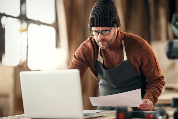 Koncentrerad Vuxen Skäggig Hantverkare Med Papper Handen Kontrollera Information Bärbar — Stockfoto