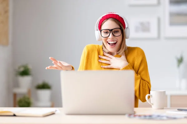 Verrukte Jonge Vrouw Koptelefoon Bril Glimlachend Gesticulerend Terwijl Aan Tafel — Stockfoto