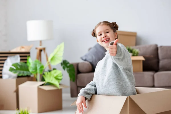 Alegre Niño Lindo Sentado Caja Cartón Mostrando Gesto Pulgar Hacia — Foto de Stock