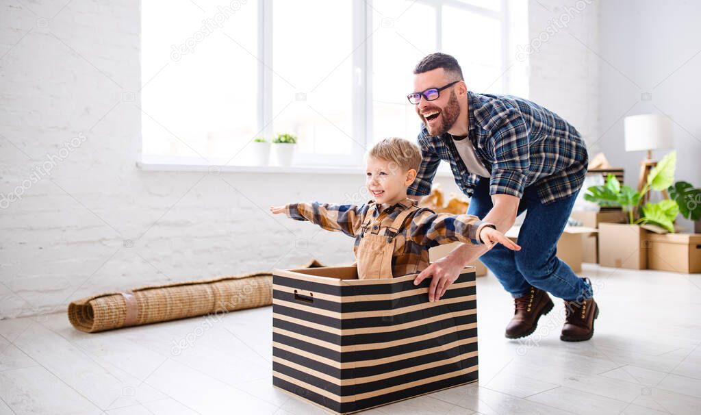 Side view of delighted father riding smiling child in box while having fun during relocation in new flat