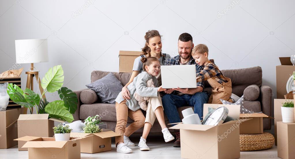 Content family sitting together on sofa in new flat with unpacked boxes and using laptop while having break during relocation