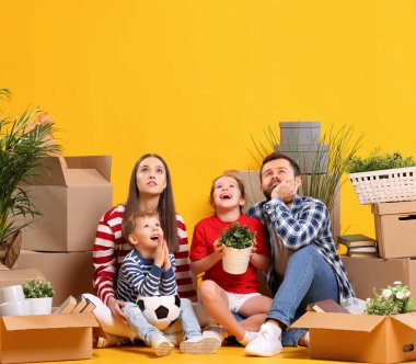 Hayalperest bir ailenin bütün bedeni: evli ve çocuklu bir çift eşyalarla dolu kutuların arasında oturuyor ve yeni bir ev hayal ediyorlar.