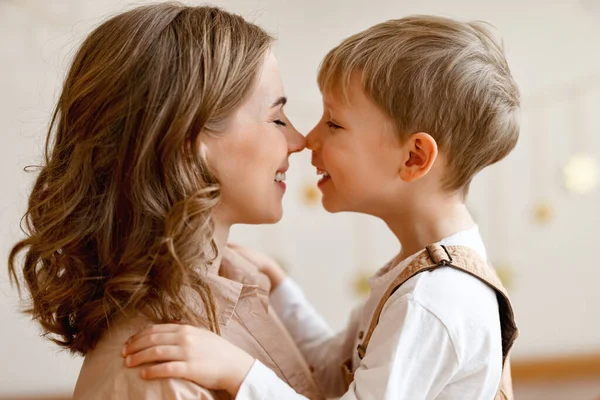 Side view of happy family: young woman and little boy in casual clothes embracing   while congratulating on holiday mothers day   at home