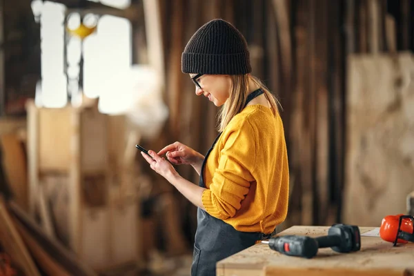 Sidovy Positiva Unga Kvinnliga Träarbetare Förkläde Meddelanden Mobiltelefon När Står — Stockfoto
