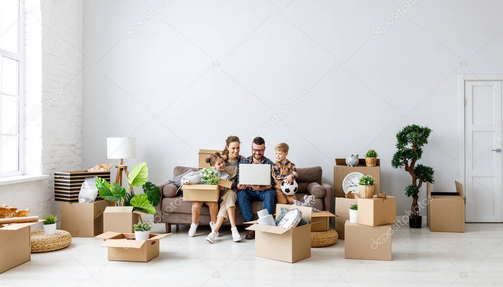 Content family sitting together on sofa in new flat with unpacked boxes and using laptop while having break during relocation