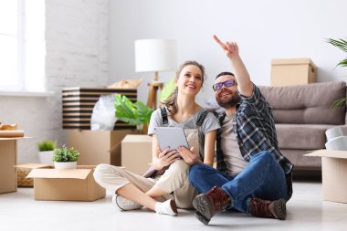 Yeni dairenin dekorasyonunu tartışırken tablet ve kutularla yerde oturan neşeli çift...
