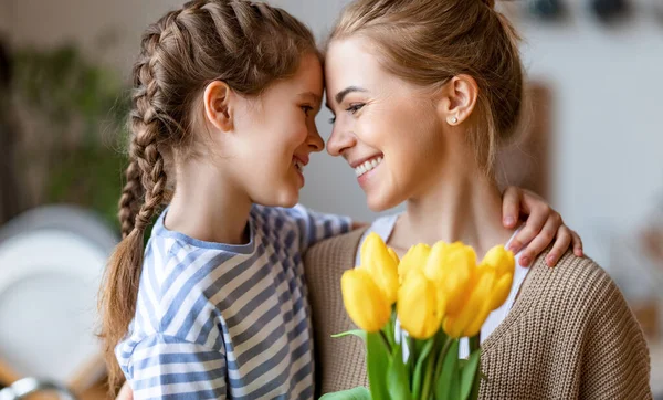 乐观的家庭 在节日庆祝活动中 母亲带着一束白色郁金香 带着快乐的女儿笑着抚摸着额头 — 图库照片