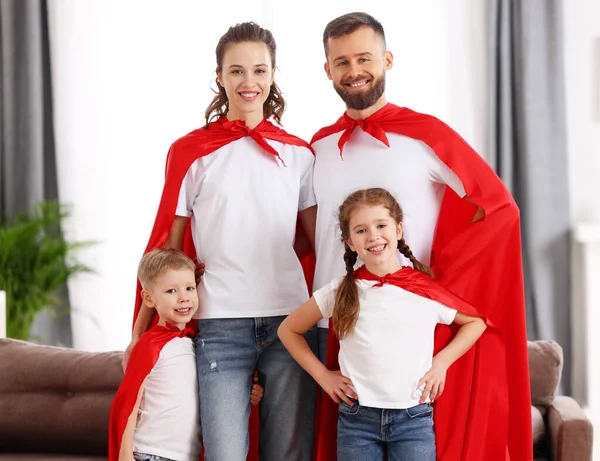 快乐的父母们 他们的小儿子和女儿穿着相似的衣服 戴着红色的超级英雄帽 一边看着相机 一边在家里玩乐 一边享受着闲暇时光 — 图库照片