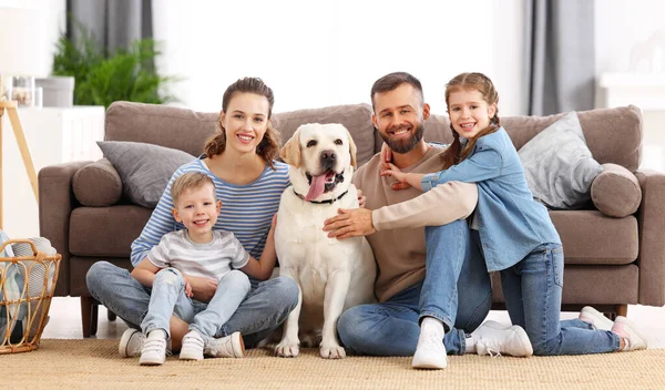 拉布拉多猎犬笑着 父母带着小孩和可爱的纯种拉布拉多猎犬坐在地板上 一边看着摄像机 一边在家里呆着 — 图库照片