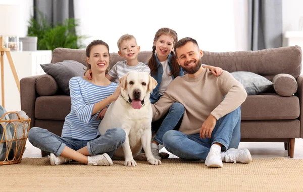 拉布拉多猎犬笑着 父母带着小孩和可爱的纯种拉布拉多猎犬坐在地板上 一边看着摄像机 一边在家里呆着 — 图库照片