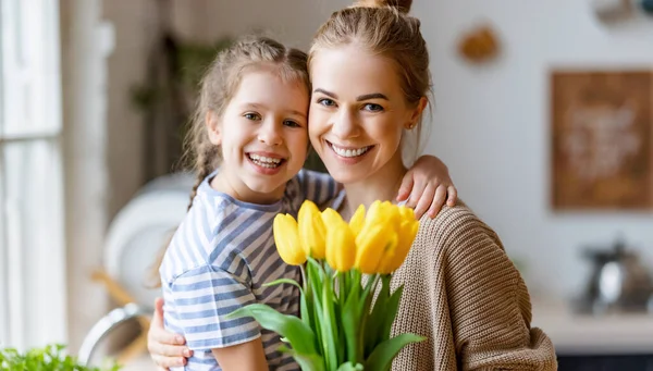 Любящая Маленькая Дочь Обнимает Счастливую Маму Приветствует Букет Желтых Тюльпанов — стоковое фото