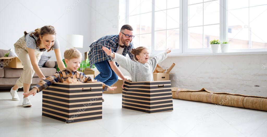 Playful family: parents riding kids in boxes and having fun during moving in new spacious apartment