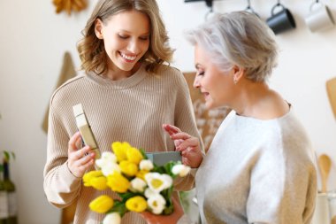 Bir sürü taze lalesi olan zarif, yaşlı bir kadın anneler günü kutlamalarında küçük bir kızın hediyesini kabul ediyor.