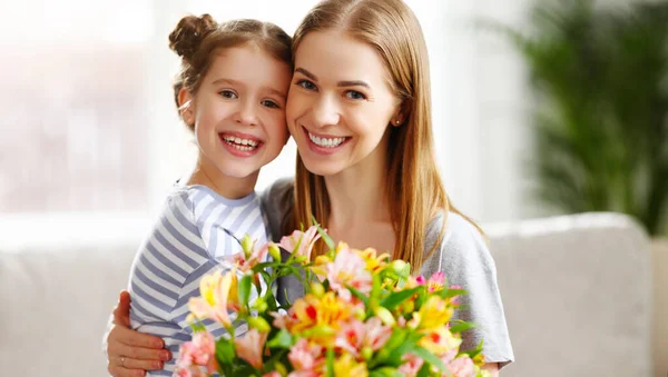 Fröhliches Kind Umarmt Frau Auf Sofa Sitzend Mit Blumenstrauß Von — Stockfoto