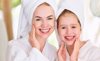 Kafasında havlular, bornozlar temiz yüzlere dokunuyor ve kameraya gülümsüyor.