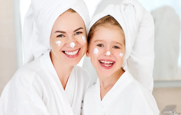 迷人的女孩 妈妈头戴毛巾 脸上挂着乳白色的污迹 在浴室里对着相机微笑 — 图库照片