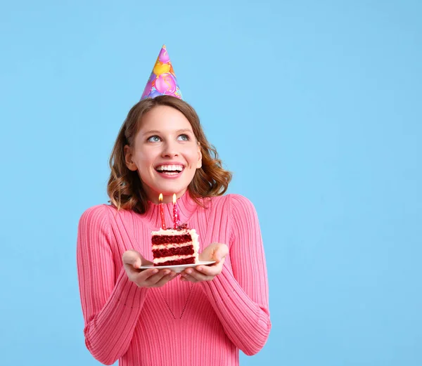 お誕生日のお祝いの間に願い事をしながら お菓子やパーティーの帽子で幸せな女性はろうそくとカップケーキを保持し 笑顔で離れて見て — ストック写真