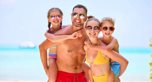 Laughing Parents Giving Piggyback Ride Cheerful Children Vivid Swimsuits Smiling — Stock Photo, Image
