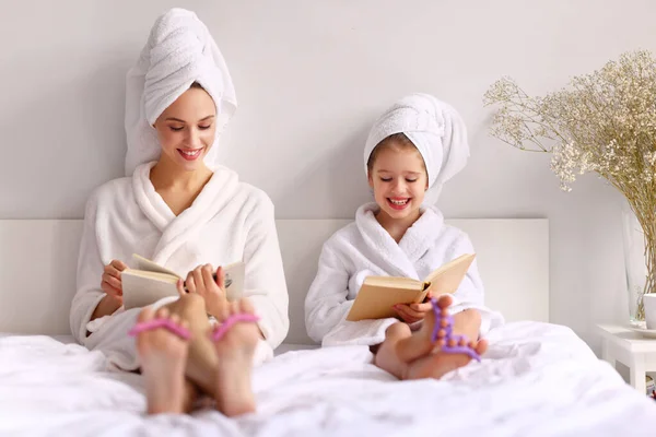 Feliz Joven Madre Hija Batas Baño Toallas Sonriendo Mientras Lee — Foto de Stock