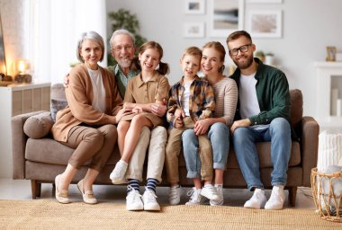 Büyük mutlu bir aile. Büyükbaba, anne, baba ve iki sevimli çocuğun portresi, kız kardeş ve erkek kardeş, evde otobüste oturup kameraya gülümsüyorlar. İpotek kredisi ve emlak konsepti