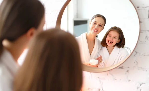 Conteúdo Jovem Mãe Filha Roupões Banho Brancos Aplicando Creme Cosmético — Fotografia de Stock