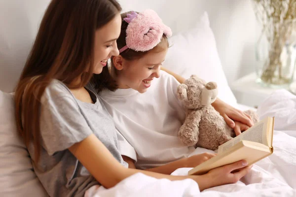 Alegre Madre Abrazando Hija Mientras Descansan Cama Leen Libro Juntos —  Fotos de Stock