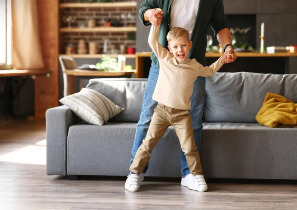 リビングルームでお父さんと一緒に踊る幸せな小さな男の子の完全な長さのショット 父親の手を保持し カメラで笑顔 幸せな家族のパパと子供が一緒に遊んで 自宅で余暇を楽しむ — ストック写真