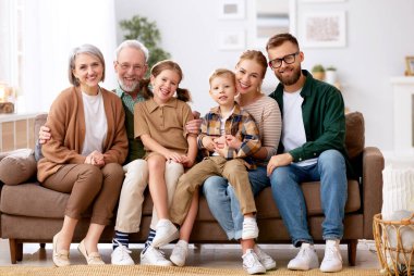 Büyük mutlu bir aile. Büyükbaba, anne, baba ve iki sevimli çocuğun portresi, kız kardeş ve erkek kardeş, evde otobüste oturup kameraya gülümsüyorlar. İpotek kredisi ve emlak konsepti
