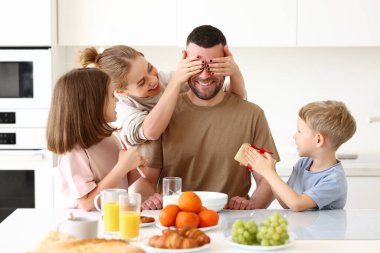 Baban için süpriz. Şirin gülümseyen çocuklar babalarına hediye paketi ve kartpostal veriyorlar. Genç anne, mutfakta kahvaltı ederken kocasını çocuklarıyla tebrik ediyor. Aile tatili kavramı
