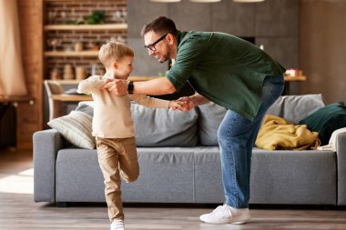 Babanızla eğleniyorsunuz. Sevimli, heyecanlı bir çocuk ve rahat giyinen, dans eden ve evde otururken birlikte çalan genç bir baba. Aile eğlence aktiviteleri