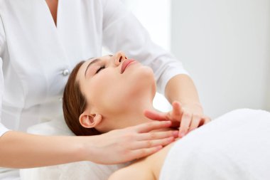 Güzellik uzmanı ya da masör genç bir kadın için miyofasyal ya da buktal kafa ve yüz masajı yapıyor. Kadın hasta spa merkezinde yatıyor, yaşlanmayı önleyen güzellik tedavisi görüyor. Cilt tazeleme kavramı