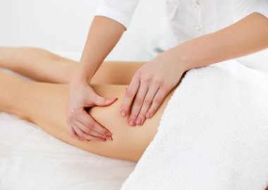 Beauty treatments for weight lost. Cropped shot of therapist or masseur doing lymphatic drainage or anti cellulite massage on legs for woman client lying at spa center. Body care concept clipart